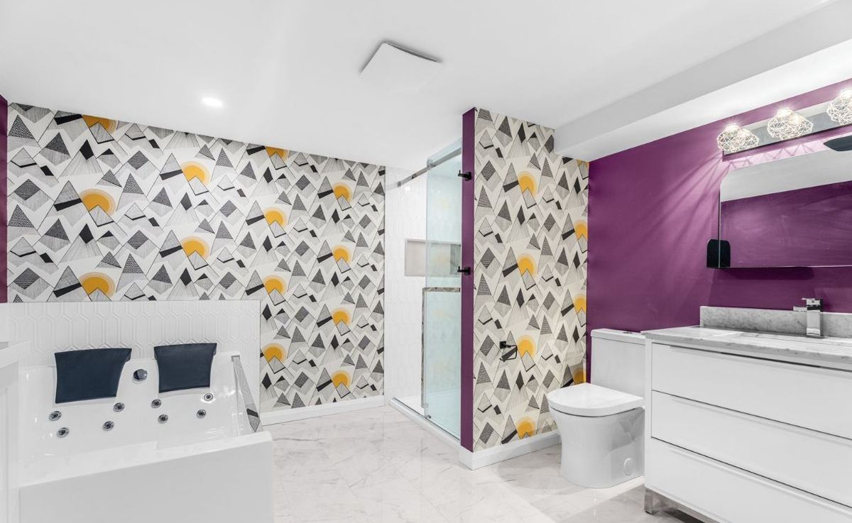 Basement bathroom with geometric feature wallpaper and a jetted tub