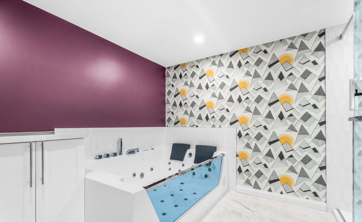Basement bathroom with a jetted tub and a patterned feature wall