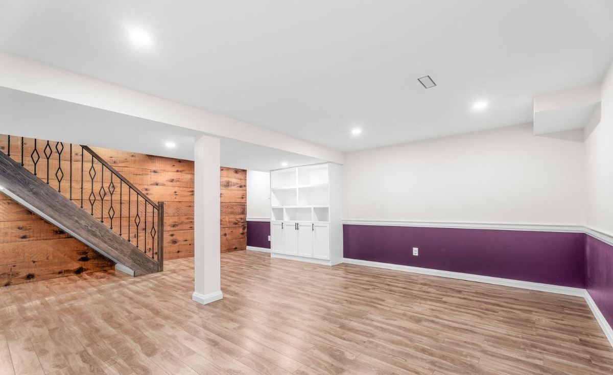 Finished basement with a wood feature wall, new staircase and built-in shelving