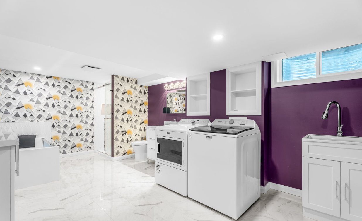 Basement laundry room with side-by-side washer and dryer and a utility sink