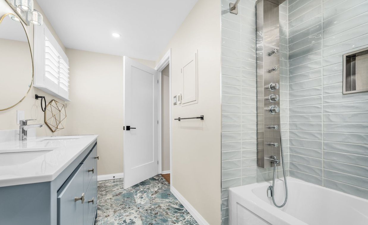 Renovated bathroom with a tiled tub and shower and a rain shower panel