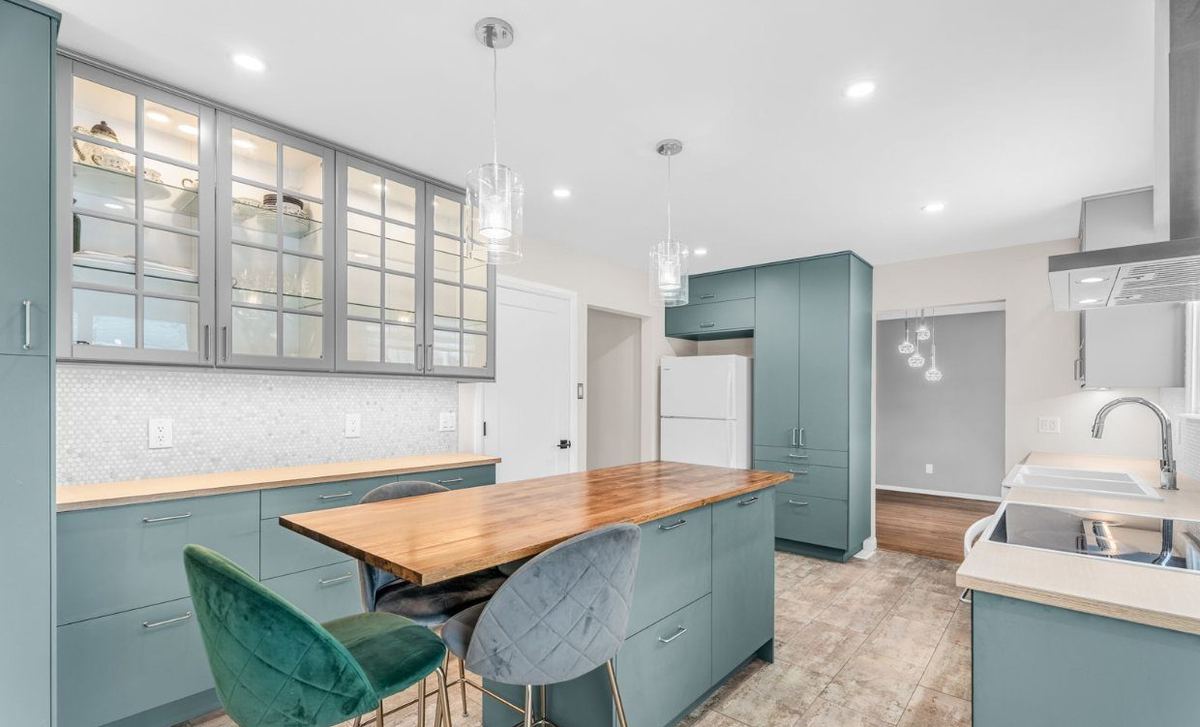 Custom kitchen cabinets with glass display uppers and a dining table under pendant lights