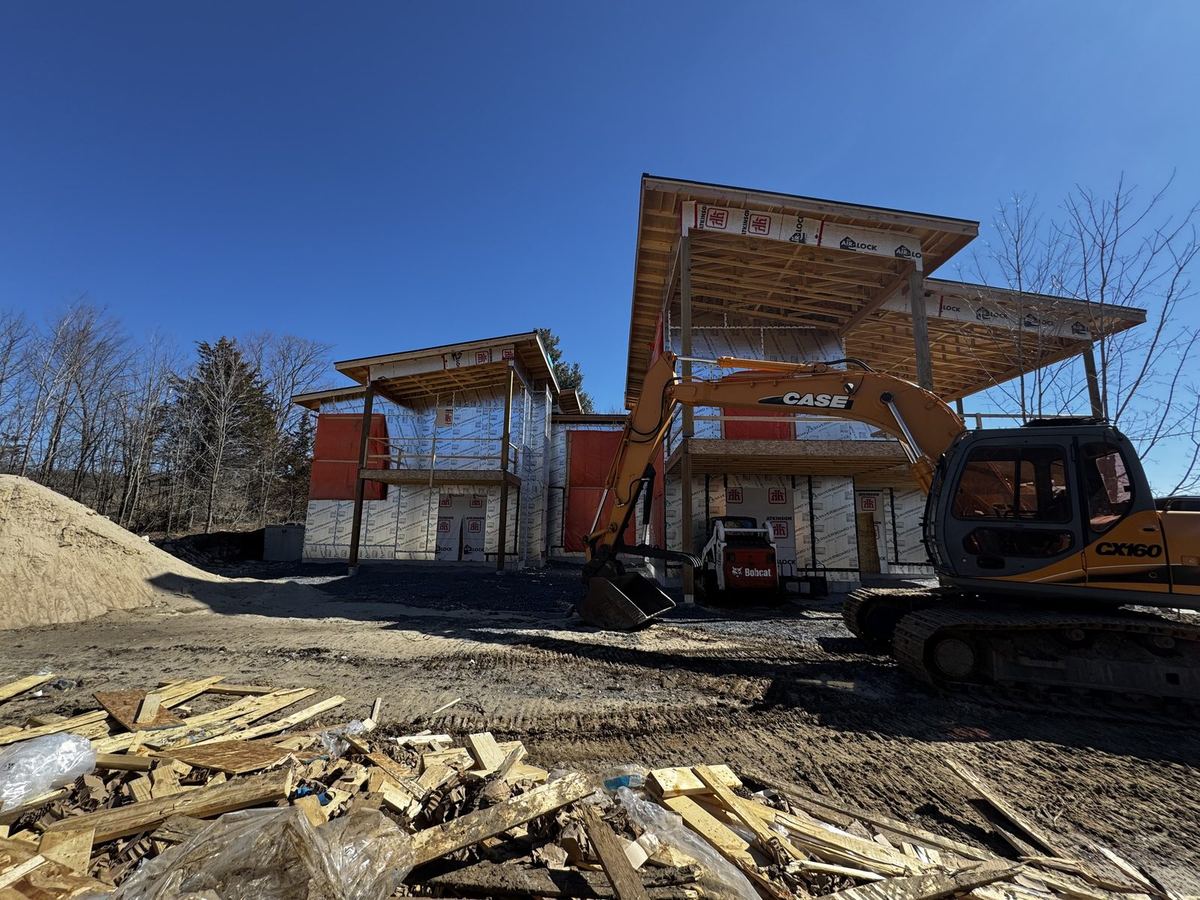 Excavator on site at a modern custom home under construction