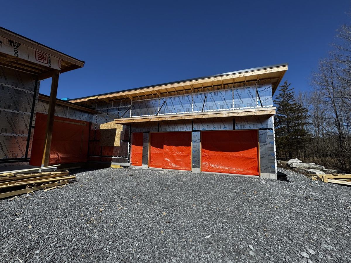 Modern custom home under construction with a timber-framed roofline and attached garages