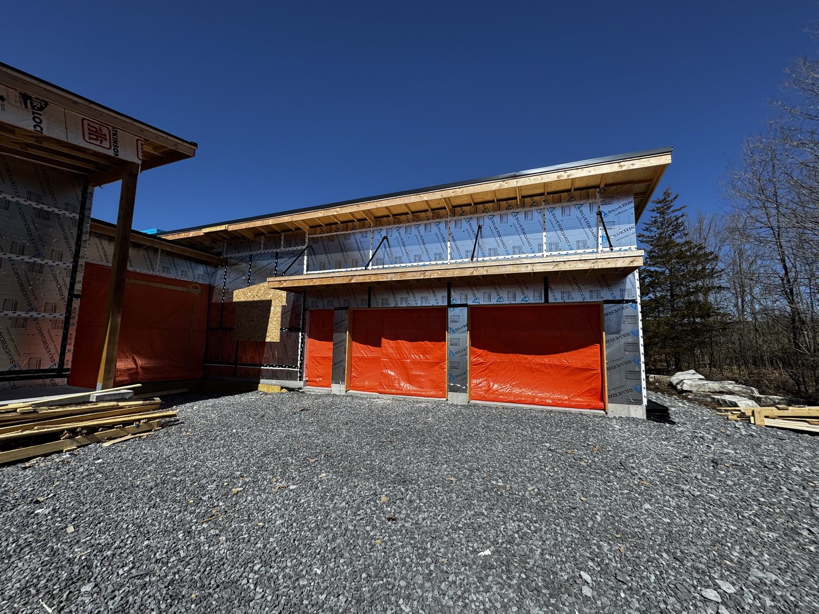 Modern custom home under construction with a timber-framed roofline and attached garages