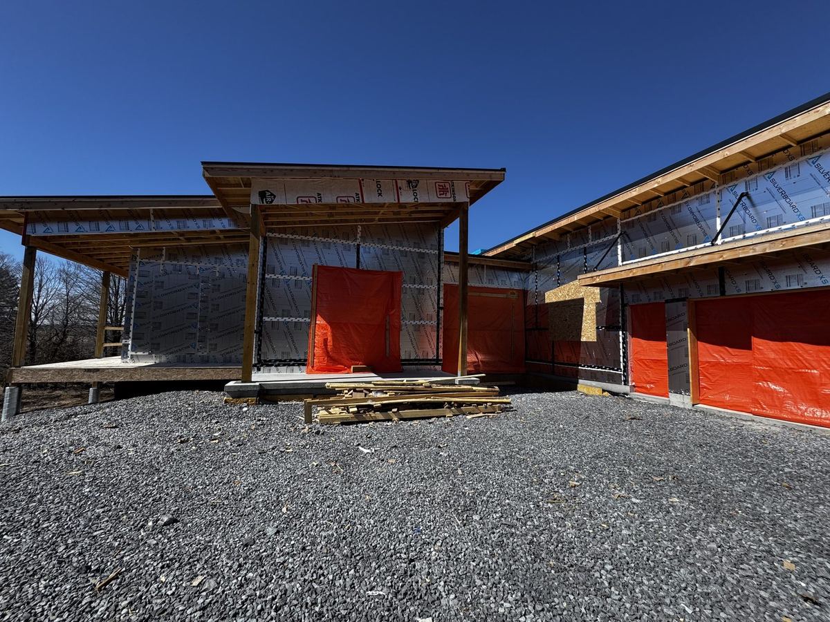 Modern custom home with attached garages and covered timber porches, during construction