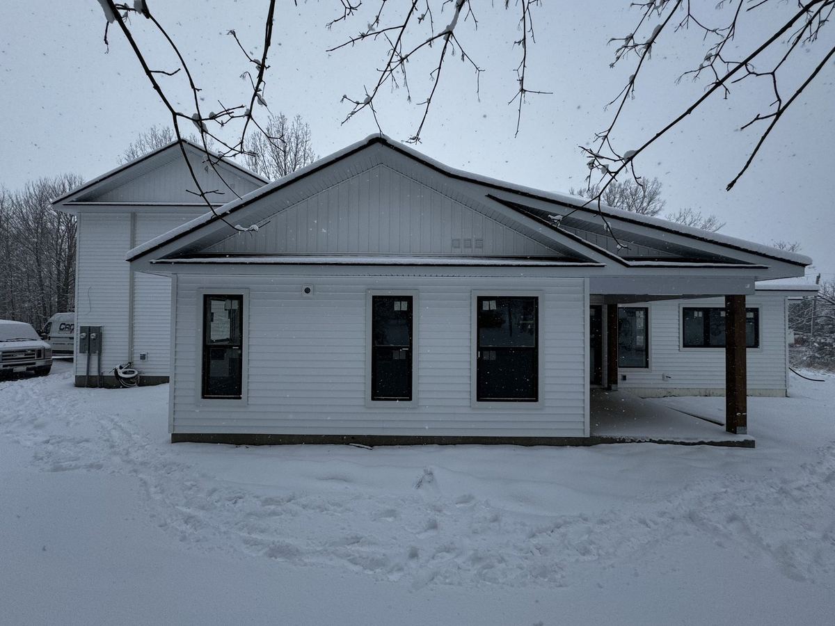 Newly built bungalow with white siding and black windows in winter