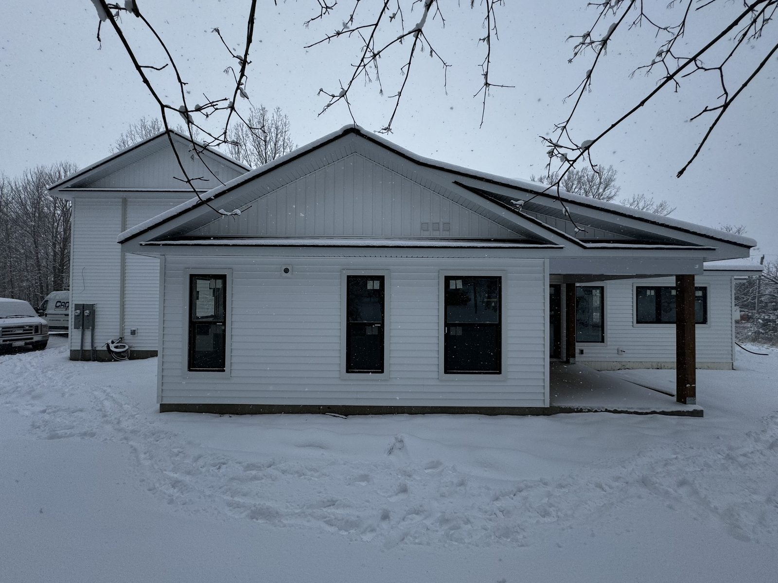 Newly built bungalow with white siding and black windows in winter
