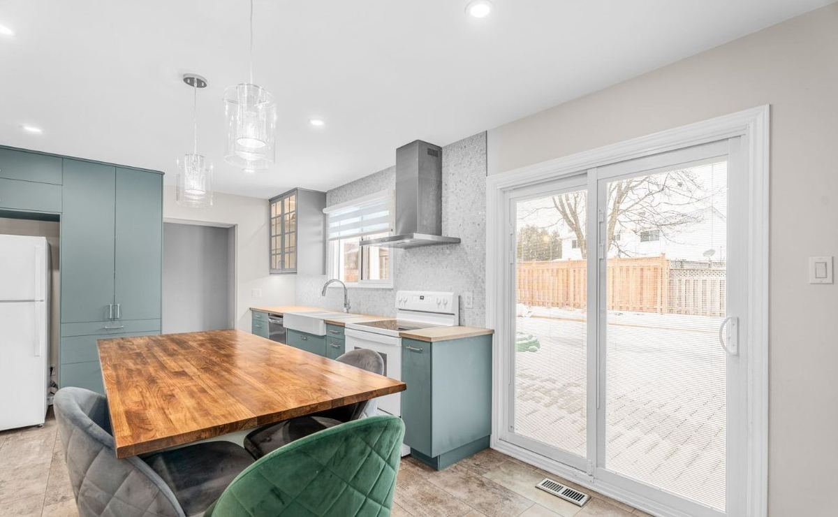 Open-concept kitchen and dining area with a butcher-block table and patio doors