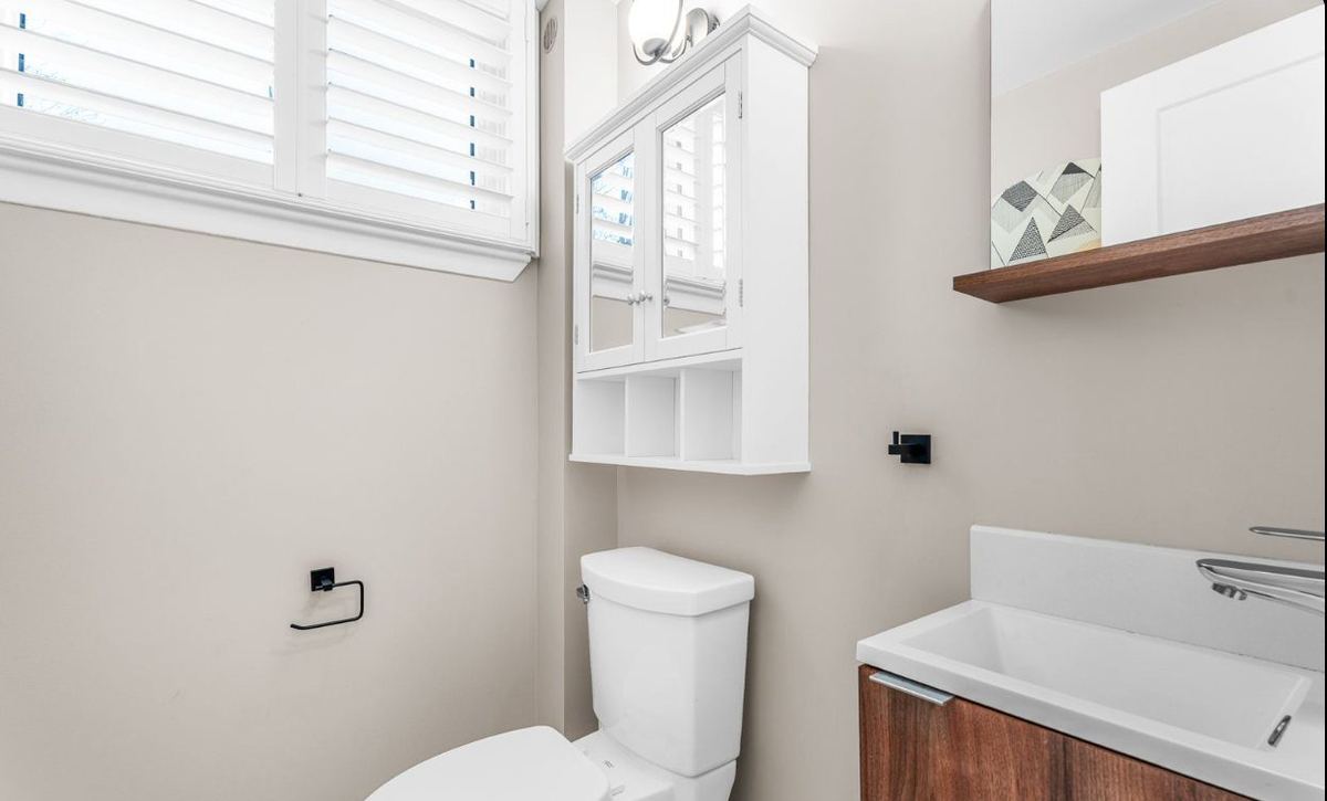 Powder room with a walnut vanity and white wall cabinets