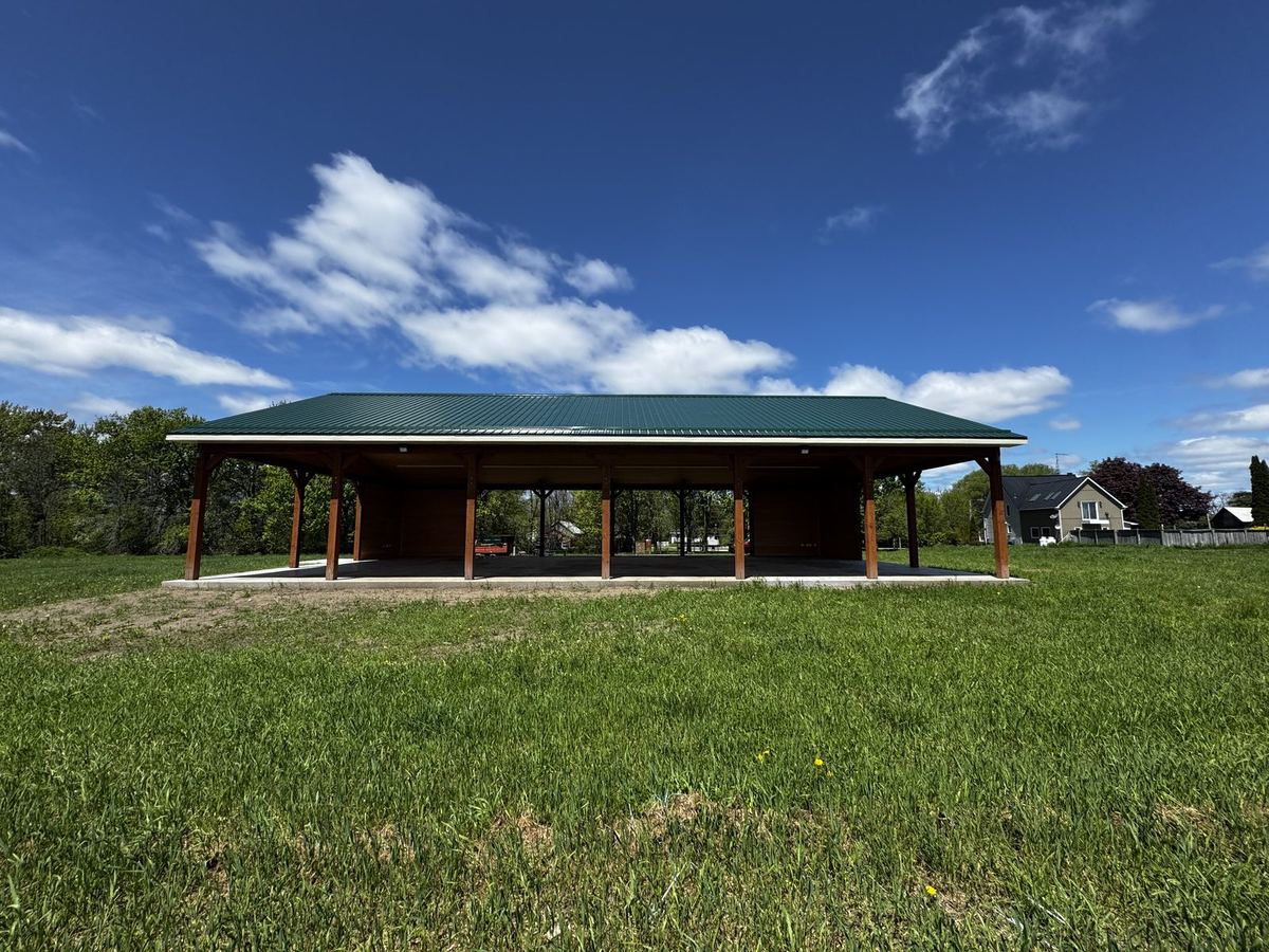 Timber pavilion with a metal roof in an open field